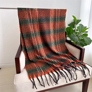 Detail of plaid scarf featuring orange and green checks with long tassel trim texture
