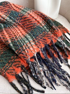 Detailed shot of the thick plaid knit scarf texture with fringe and retro grid pattern