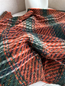 Close-up of tartan plaid scarf fabric with orange and green patterns and fringe