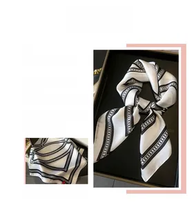 Macro detail of silk-like scarf featuring classic black and white geometric chain print