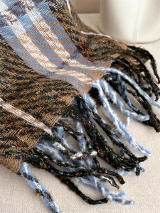 Close-up of checkered scarf with fringe details and colorful neps in winter style