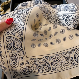 Detailansicht eines Seiden-Halstuchs mit Paisley-Muster in Cremeweiß und elegantem Marineblau