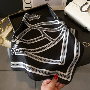 Close-up of luxury silk scarf featuring elegant metal chain and geometric patterns