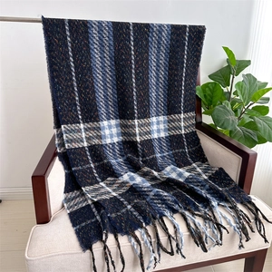 Close-up of classic navy blue plaid scarf with white accents and fringe on a chair
