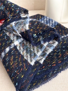 Detailed close-up of thickened plaid knit scarf showing navy fabric and fringe texture