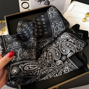 Nahaufnahme von schwarz-weißem Seidenschal mit Paisley-Muster in luxuriöser Geschenkbox