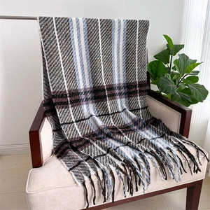 Detail view of thick soft plaid scarf with fringe on chair, grey and blue checkered pattern