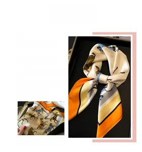 Detail eines Seidenschals mit Pferdeprint, Reitmotiv und orangefarbenem Kontrastrand