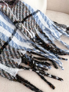 Detailed view of plaid scarf with thick tassels and soft orange-green fiber accents