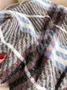 Macro detail of plaid scarf fabric texture with colorful flecks and soft fringe edge