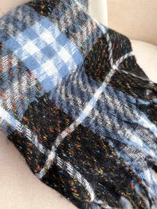 Macro detail of thick checkered plaid scarf fabric texture and frayed fringe tassels