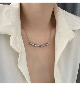 Dettaglio della collana d'argento in metallo liquido con ciondolo a onde su camicia