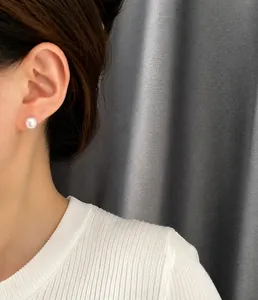 Primer plano de un pendiente de perla blanca natural minimalista usado por una modelo