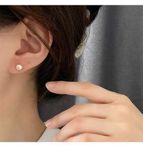 Primer plano de pendientes de plata S925 con una perla blanca natural de diseño sencillo