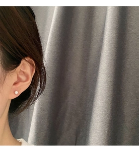 Primer plano de una modelo con un pendiente de tuerca de perla natural blanca redonda