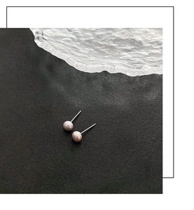 Primer plano de pendientes de perlas naturales sobre un fondo oscuro texturizado