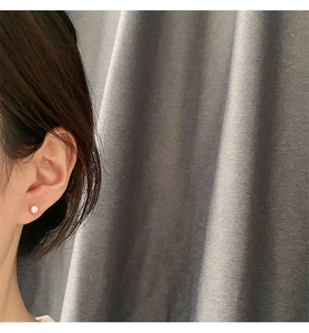 Primer plano de pendiente de perla natural minimalista en el lóbulo de la oreja de modelo