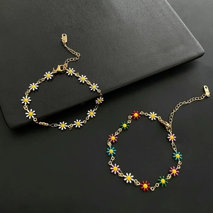 Colorful and white daisy flower bracelets with gold metal chain on black background