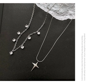 Détail des colliers en argent avec étoile et zircon sur un fond noir texturé élégant