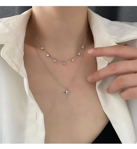 Gros plan d'un collier double épaisseur argenté avec pendentifs étoile et zircon