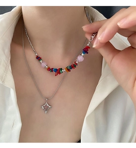 Close-up of layered necklaces with colorful stone beads and star pendant on a white shirt