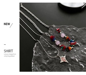Detail of colorful beaded silver chain and star pendant necklace on textured glass