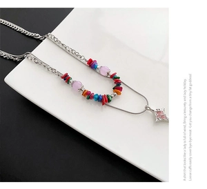 Macro detail of a double-layered necklace with colorful stones and a pink star charm