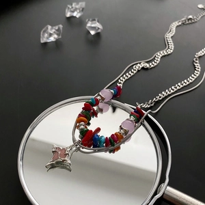 Colorful layered beaded necklace with star pendant and mixed stone accents on mirror surface