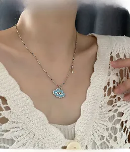 Detail of blue enamel cloud smile pendant with pavé zircons worn on a beaded chain