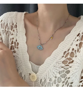 Detail of blue smiling cloud pendant necklace with enamel lightning charm on neck