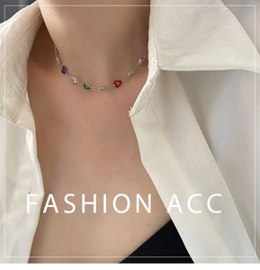 Detail of colorful heart charm necklace with sparkling crystals worn on the neck
