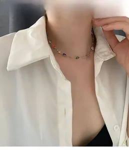 Close-up of golden necklace with colorful heart charms on a model wearing white shirt