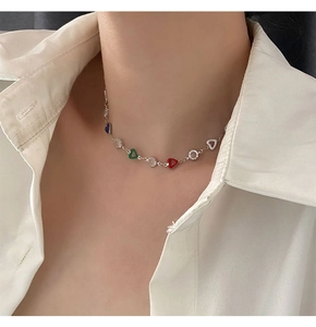Macro view of silver-tone chain necklace with colorful heart pendants on a model