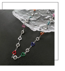 Detail of colorful heart pendants and round zircons on a silver chain necklace