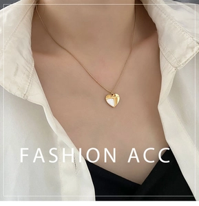 Détail d'un collier cœur doré avec incrustation de nacre porté pour un look élégant
