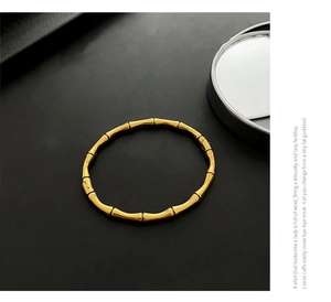 Gros plan sur le bracelet jonc doré style bambou minimaliste avec finition polie