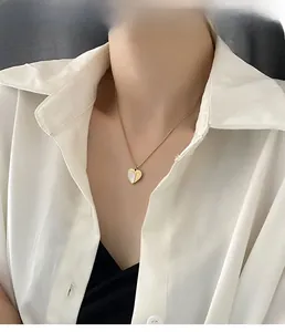 Détail d'un collier pendentif cœur doré avec incrustation de nacre porté par un mannequin