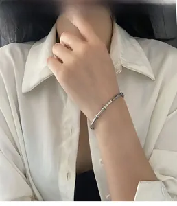 Bracelet en argent style bambou porté au poignet avec une chemise blanche