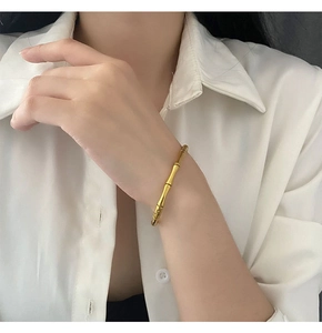 Gros plan détaillé d'un bracelet jonc doré en style bambou porté au poignet d'une femme