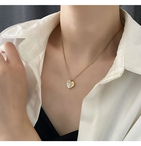 Détail d'un collier cœur minimaliste doré avec nacre porté par un mannequin en chemise