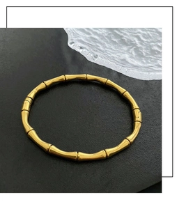 Détail macro du bracelet à nœuds de bambou doré poli sur surface texturée sombre