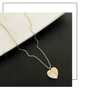 Détail d'un collier pendentif cœur doré avec incrustation de nacre sur plateau blanc