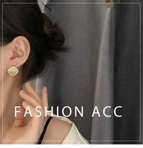 Detailed view of square gold stud earring with marbled yellow stone on a model