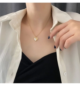 Gros plan d'un collier cœur doré avec métal poli et incrustation de nacre sur une chaîne