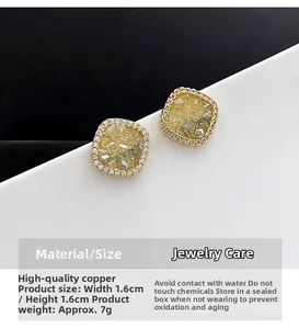 Detail view of square gold earrings featuring premium copper and yellow crystal stones