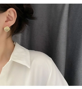 Detail shot of geometric square crystal stud earrings with gold plating on ear