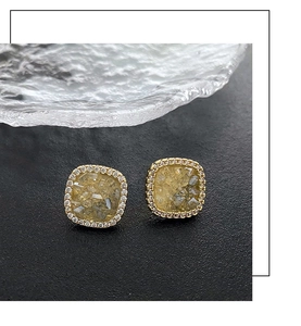 Macro shot of square gold stud earrings with yellow crystal and pave zircon border