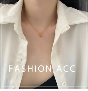 Close-up of a minimalist gold waterdrop necklace worn by a model in a white shirt