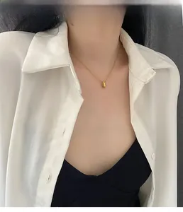 Close-up of golden teardrop pendant necklace worn by model on a refined chain