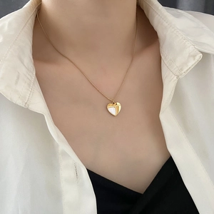 Élégant collier avec pendentif cœur doré et nacre porté sur le cou d'une femme